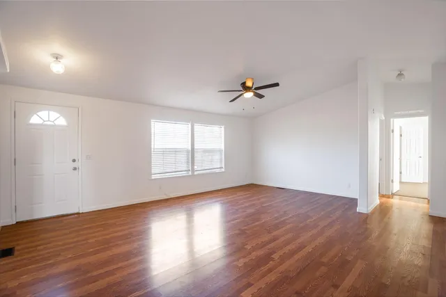a view of empty room with wooden floor and fan
