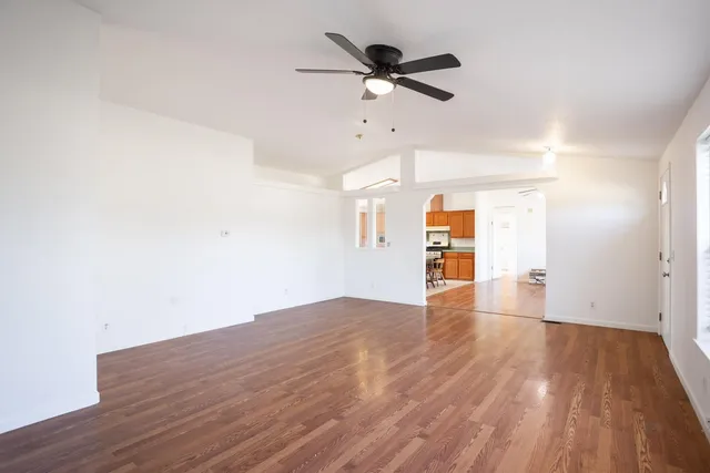 a view of empty room with wooden floor and ceiling fan