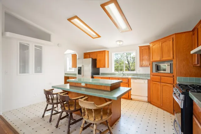 a dining room with stainless steel appliances kitchen island granite countertop a table chairs and a refrigerator
