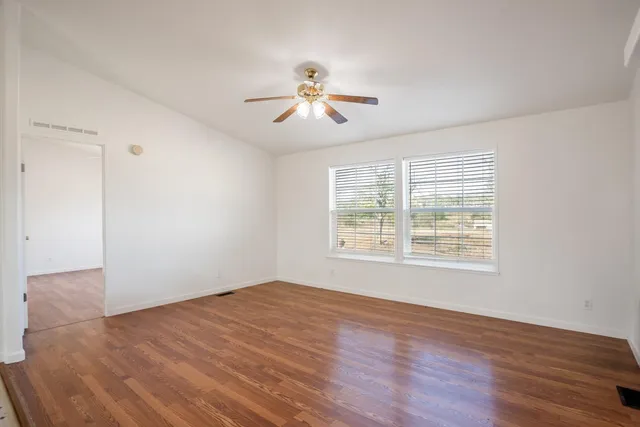 a view of empty room with wooden floor and fan