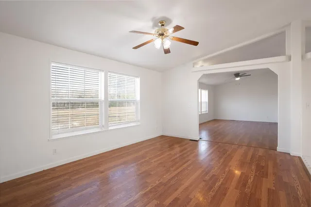 a view of an empty room with wooden floor and a window