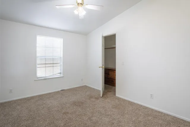 an empty room with closet and a chandelier fan