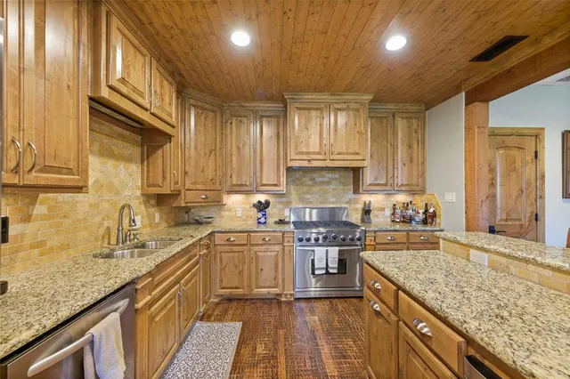 a kitchen with stainless steel appliances granite countertop a sink stove and cabinets