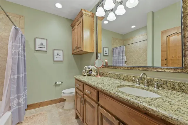 a bathroom with a granite countertop sink a toilet and a mirror