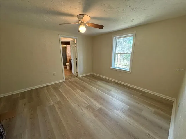 a view of an empty room with window and chandelier fan
