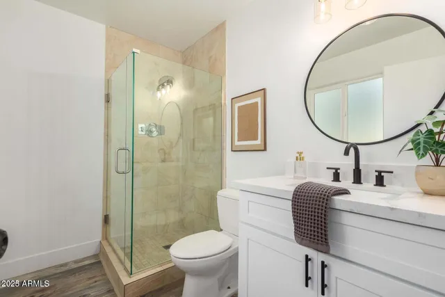 a bathroom with a granite countertop sink toilet a mirror and shower