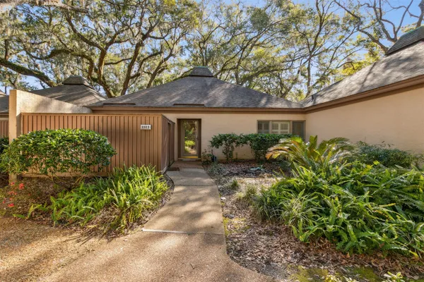 a backyard of a house with a large tree and plants