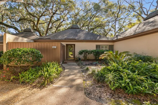 a backyard of a house with potted plants and large tree