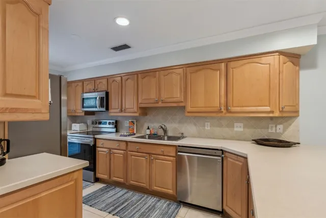 a kitchen with stainless steel appliances granite countertop a sink a stove a refrigerator with grey cabinets