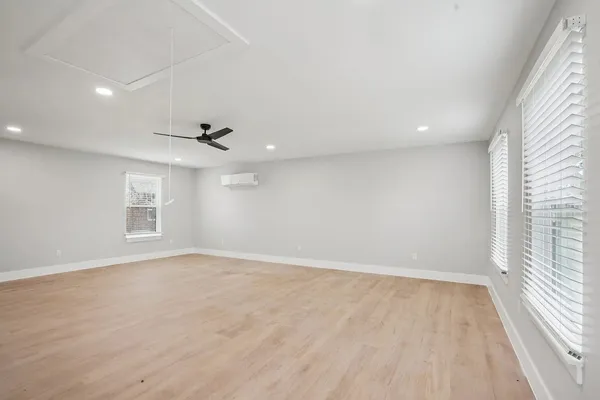 an empty room with wooden floor ceiling fan and windows