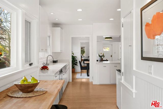 a large white kitchen with lots of counter top space and stainless steel appliances