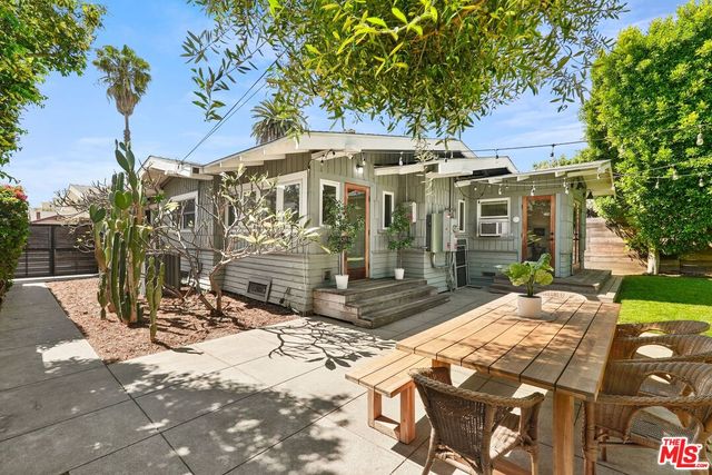 a view of a white house with a large tree