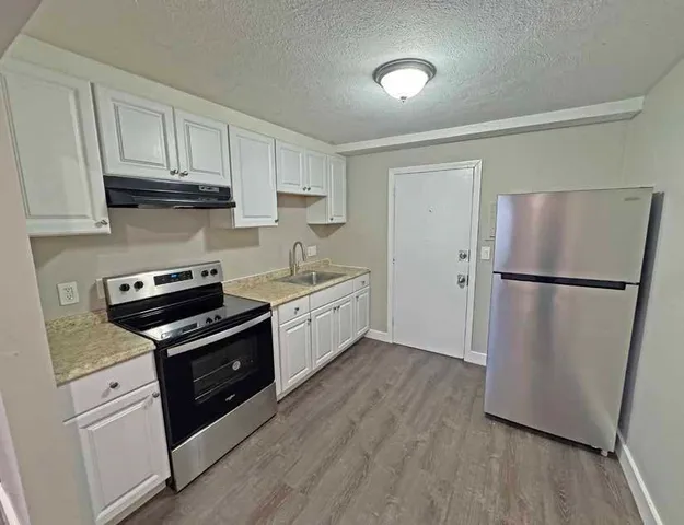 a kitchen with granite countertop a refrigerator stove and sink