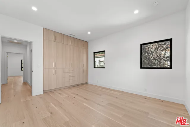a view of an empty room with wooden floor and closet