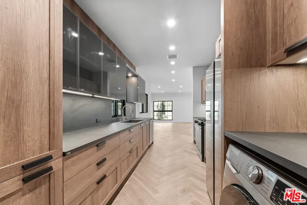 a large kitchen with stainless steel appliances a large counter top a stove and a refrigerator