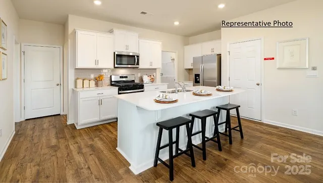 a kitchen with stainless steel appliances kitchen island granite countertop a stove a sink a microwave and a refrigerator