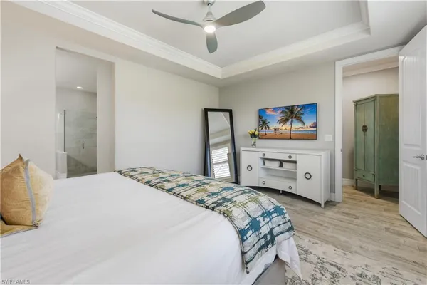 a bedroom with a bed a dresser and a chandelier