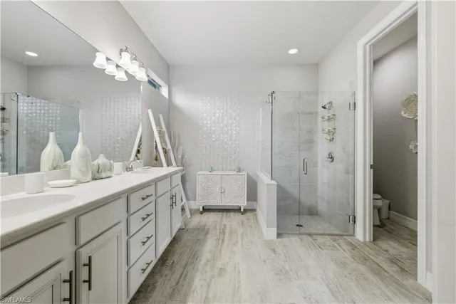 a spacious bathroom with a double vanity sink a large mirror and shower