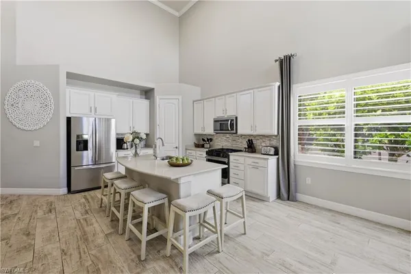 a kitchen with stainless steel appliances granite countertop a refrigerator a stove top oven a sink dishwasher and white cabinets with wooden floor