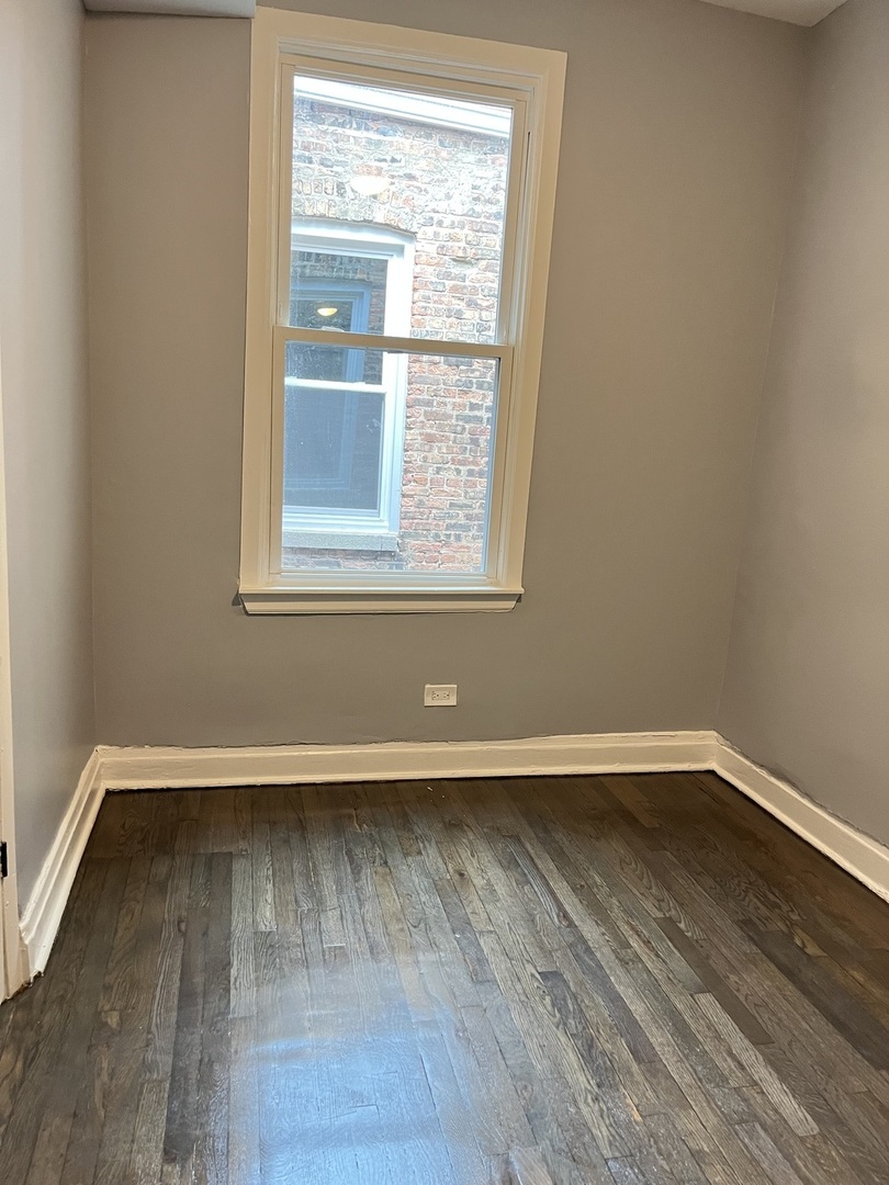 3821 West Fillmore Street, Unit 1R Chicago, IL 60624 - Photo 11 of 14 a view of an empty room with wooden floor and a window
