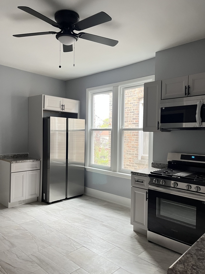 3821 West Fillmore Street, Unit 1R Chicago, IL 60624 - Photo 2 of 14 a kitchen with stainless steel appliances a stove a microwave and a refrigerator