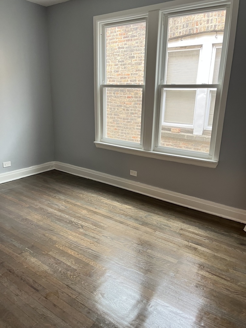 3821 West Fillmore Street, Unit 1R Chicago, IL 60624 - Photo 5 of 14 an empty room with wooden floor and windows
