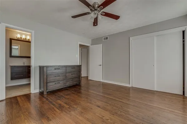 an empty room with wooden floor closet and windows