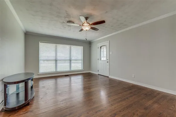an empty room with wooden floor fan and windows