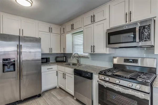 a kitchen with stainless steel appliances granite countertop a stove a microwave and a refrigerator