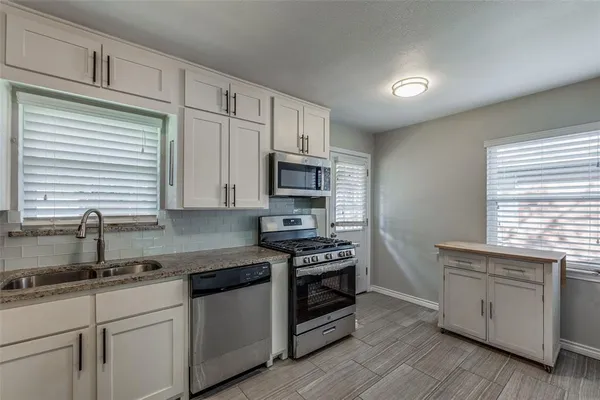 a kitchen with stainless steel appliances granite countertop a stove a sink and a microwave