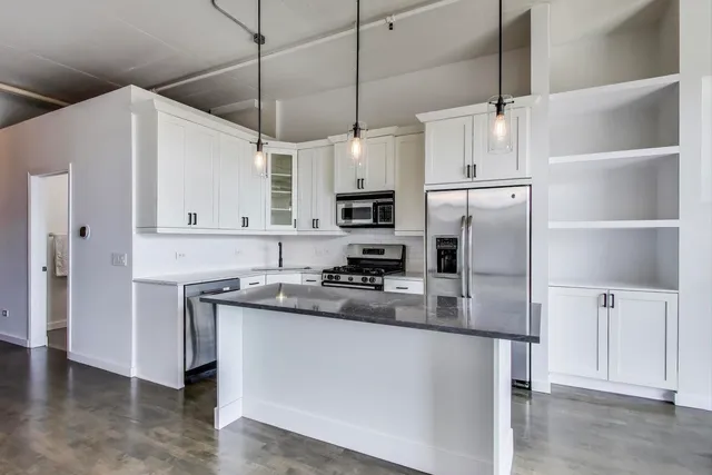 a kitchen with kitchen island a counter space a sink appliances and cabinets