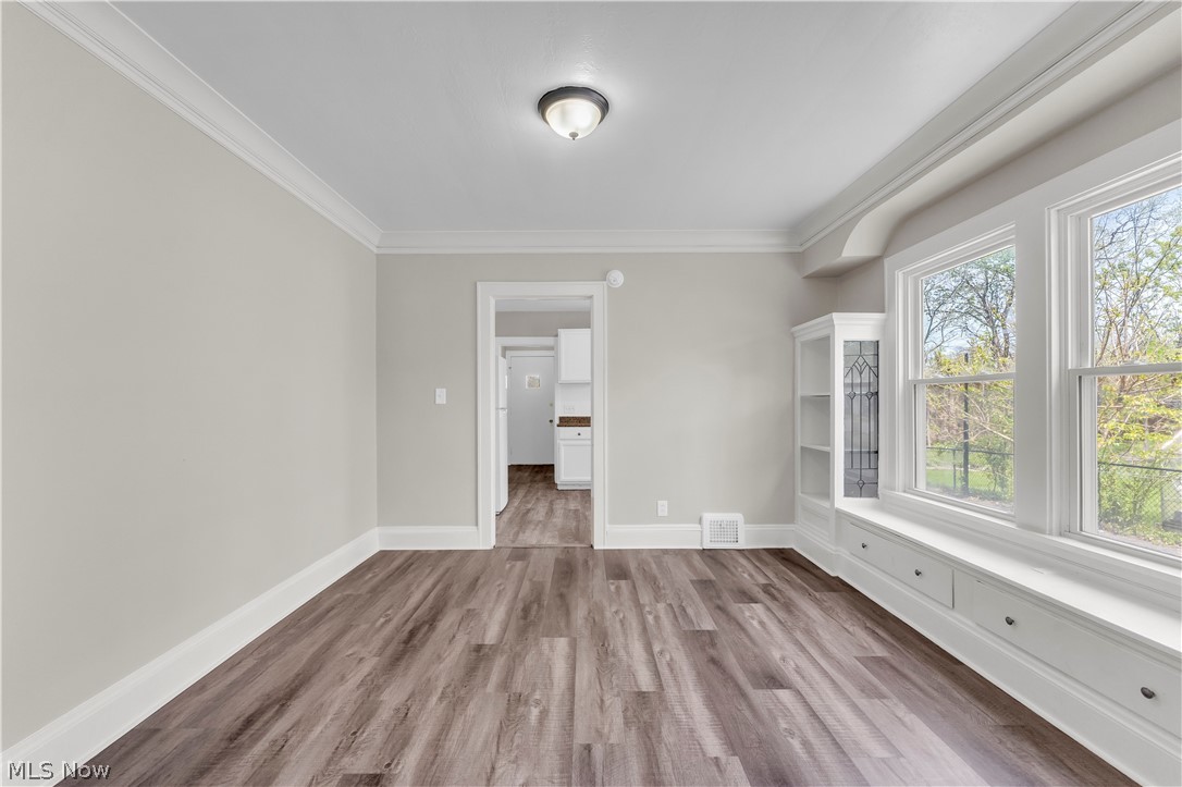 18123 McCracken Road Maple Heights, OH 44137 - Photo 10 of 27 Light-filled interior space featuring wood-finish flooring, a built-in window seat with storage, a built-in display cabinet, and crown molding