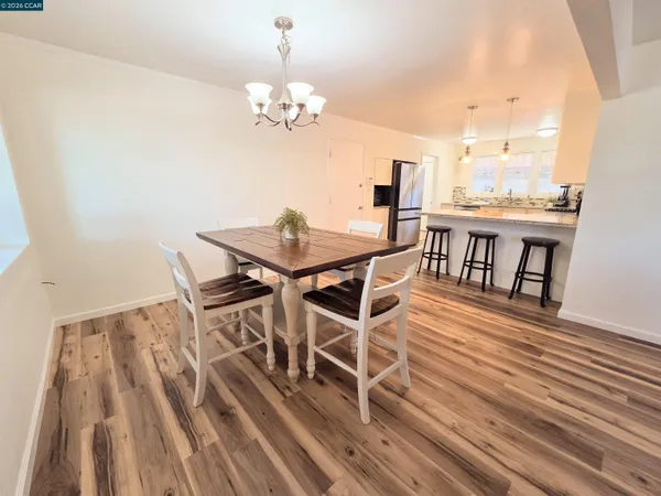 a kitchen with stainless steel appliances kitchen island granite countertop a table chairs and a refrigerator