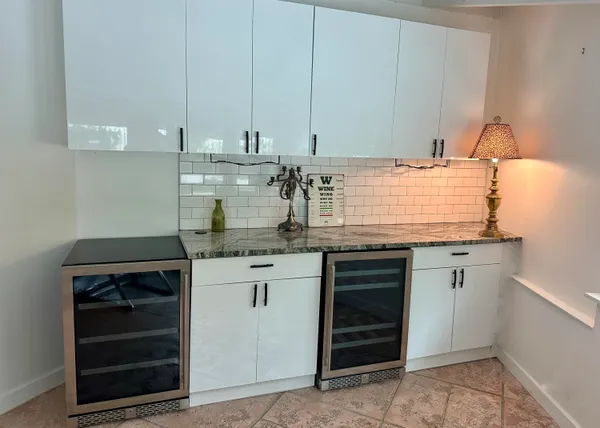 a kitchen with stainless steel appliances granite countertop a refrigerator a stove a sink and white cabinets with wooden floor