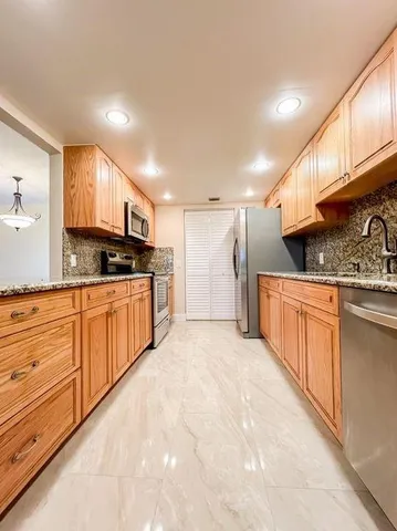 a kitchen with stainless steel appliances granite countertop a stove a sink and a refrigerator