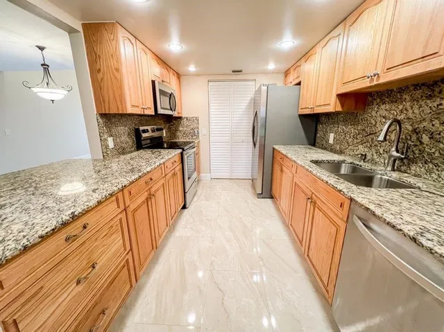 a kitchen with stainless steel appliances granite countertop a sink stove and refrigerator