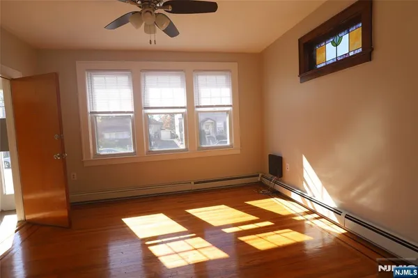 a view of empty room with wooden floor and fan