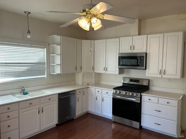 a kitchen with cabinets stainless steel appliances a sink and a window