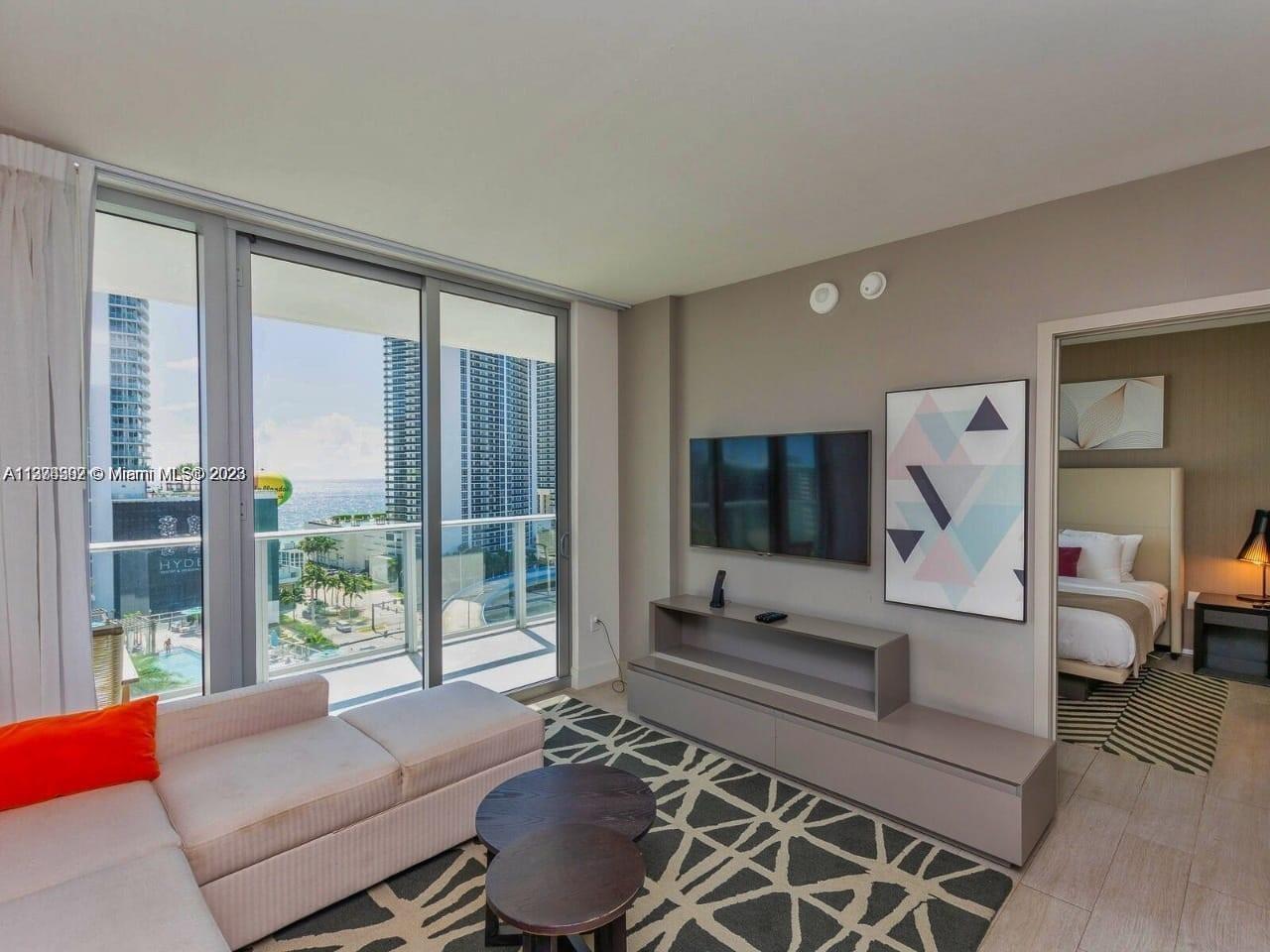 4010 South Ocean Drive, Unit R1005 Hollywood, FL 33019 - Photo 4 of 14 a living room with furniture a flat screen tv and large windows