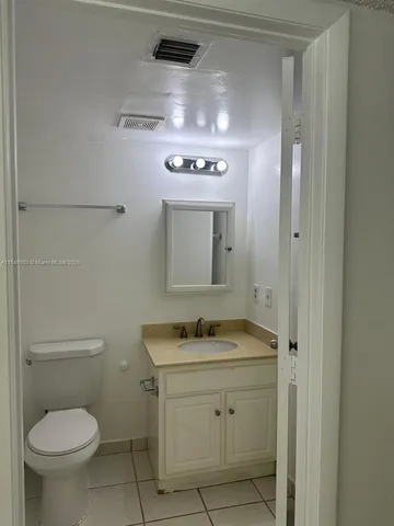 a bathroom with a granite countertop toilet sink and mirror