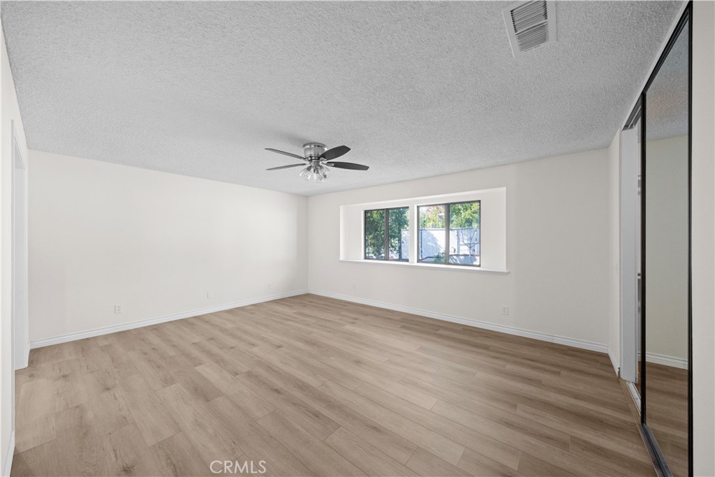 5498 Shadow Lane Rancho Cucamonga, CA 91737 - Photo 29 of 51 an empty room with wooden floor chandelier fan and windows