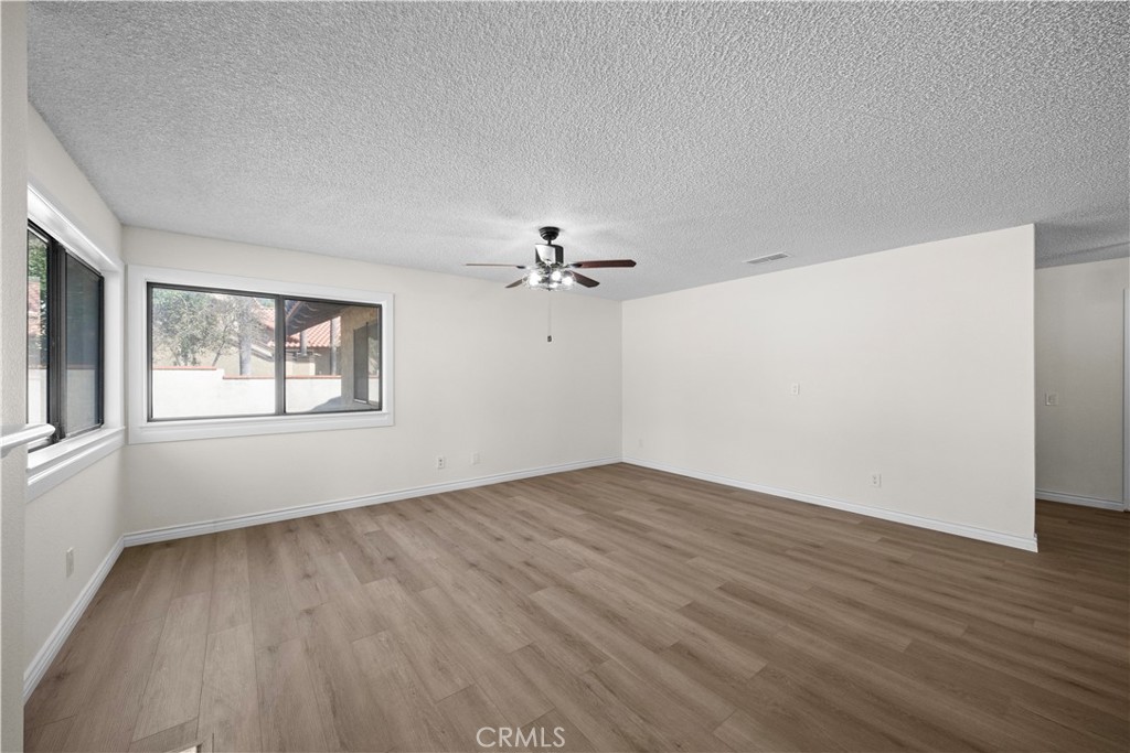 5498 Shadow Lane Rancho Cucamonga, CA 91737 - Photo 35 of 51 an empty room with wooden floor chandelier fan and windows