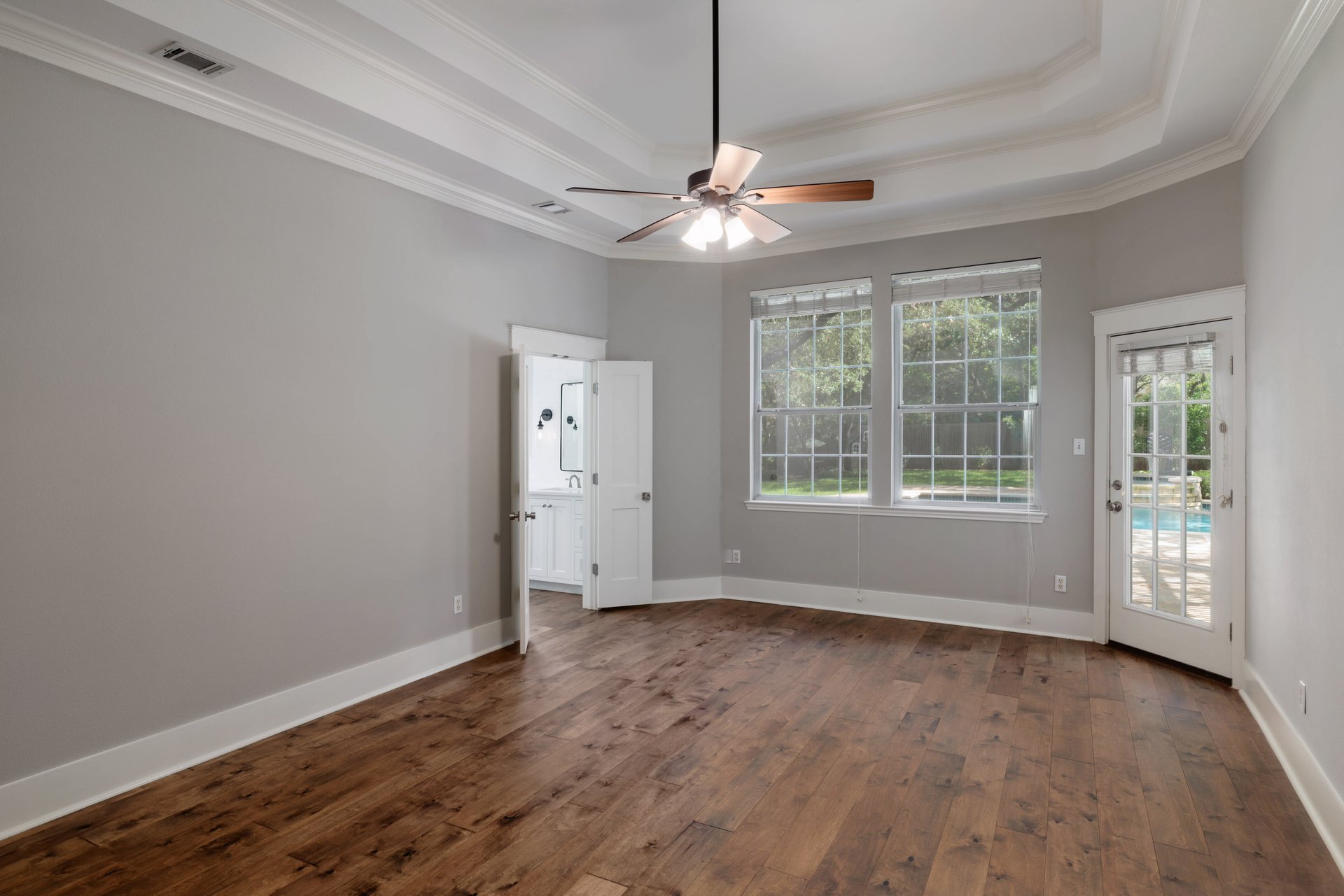 5512 Ballenton Lane Austin, TX 78739 - Photo 18 of 40 Rich hardwood floors complement a bedroom with a tray ceiling, ceiling fan, and direct access to an outdoor pool.