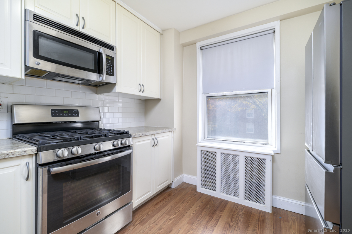 91 Strawberry Hill Avenue, Unit 331 Stamford, CT 06902 - Photo 9 of 19 a kitchen with stainless steel appliances a stove microwave and wooden floor