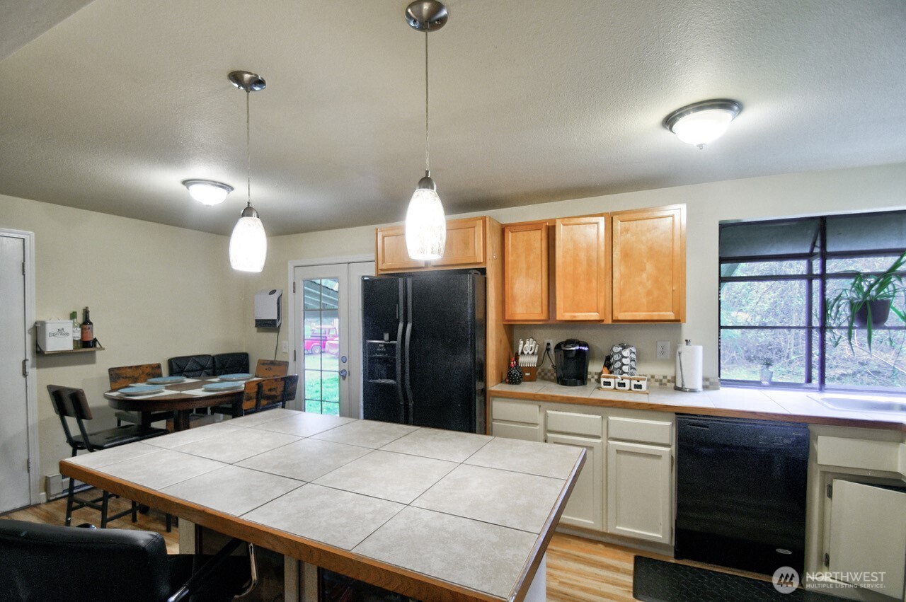 14939 Turner Road Southeast Rainier, WA 98576 - Photo 7 of 24 a kitchen with stainless steel appliances kitchen island granite countertop a refrigerator a sink dishwasher a stove and a dining table with the kitchen view