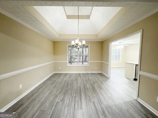 an empty room with wooden floor chandelier fan and windows