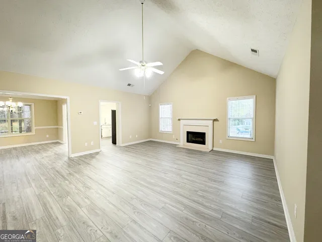 an empty room with wooden floor fireplace and windows