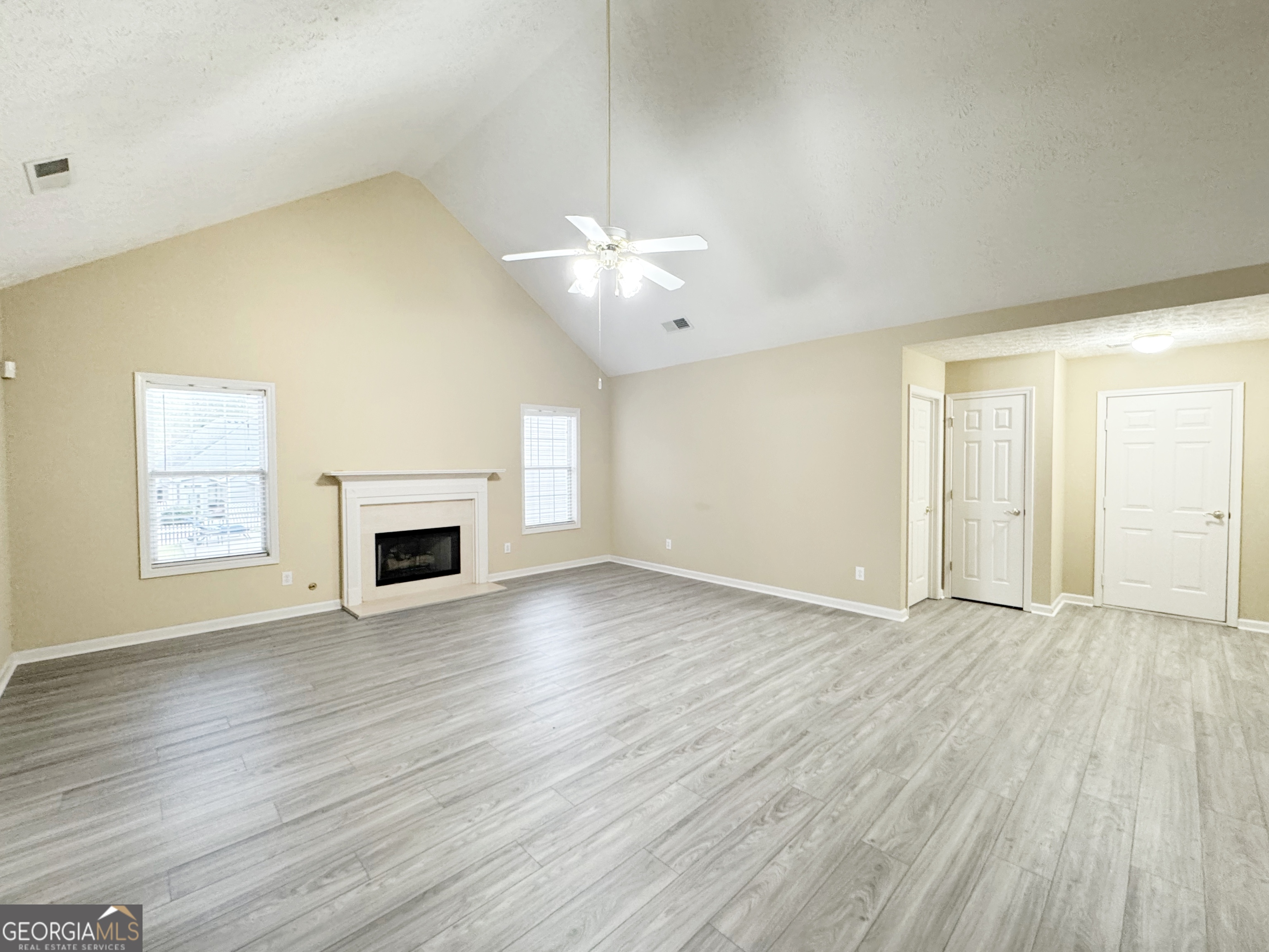 1150 Strath Clyde Way McDonough, GA 30253 - Photo 10 of 28 an empty room with wooden floor fireplace and windows