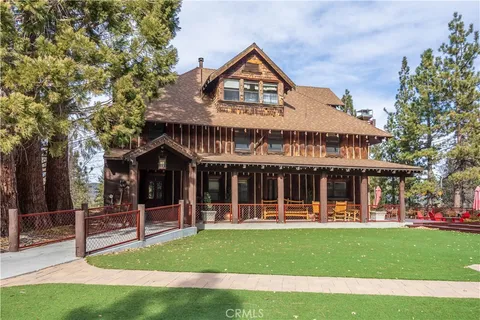 a front view of a house with a porch and a tree