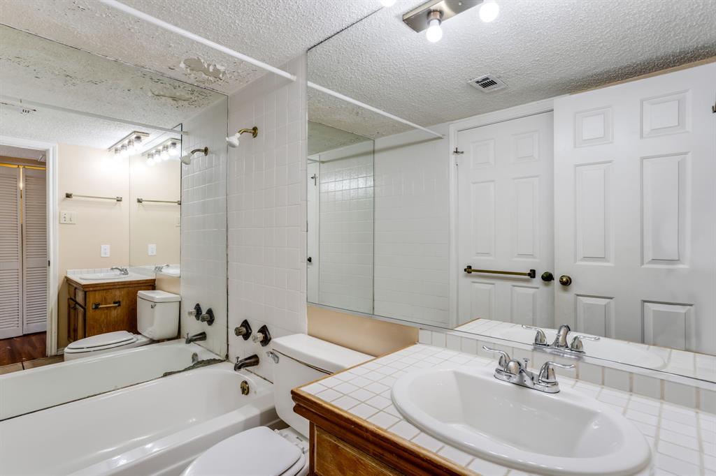 16301 Ledgemont Lane, Unit 267 Addison, TX 75001 - Photo 20 of 25 a bathroom with a granite countertop sink a toilet a mirror and shower